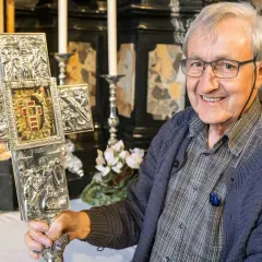 Ein Mann hält einen verzierten Kreuz mit Jesus Splitter. Die Gravuren zeigen Szenen aus dem Leben Jesu.