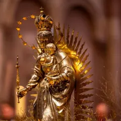 Goldene Statue der Maria mit Kind, gekrönt und mit Sternenhalo. Ein Symbol für Hoffnung und Glauben, das viele Namen trägt.
