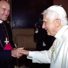 Papst Benedikt XVI. schüttelt einem Bischof die Hand. Im Hintergrund ein Kameramann und ein weiterer Geistlicher, ein Zeichen der Würde der summorum pontificum.