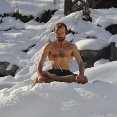 Mann in Lotussitz im Schnee, praktiziert die Wim Hof Methode.