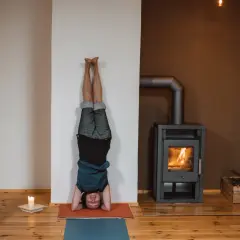 Person in einer Kopfstand-Pose, eine der vielen Iyengar Yoga Asanas, übt vor einem Kaminfeuer.