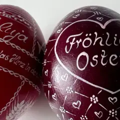 Zwei bemalte Ostereier: Ein rotes mit "Halleluja" und Anker, ein dunkles mit "Fröhliche Ostern" und Herzen. Ein schöner risus paschalis.