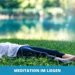 Frau genießt eine friedliche Meditation im Liegen auf einer grünen Wiese am See.