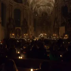 Menschen sitzen in einer dunklen Kirche, beleuchtet von Kerzen. Eine feierliche Vigil in der Kirche.
