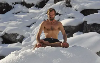 Mann in Lotussitz im Schnee, praktiziert die Wim Hof Methode.