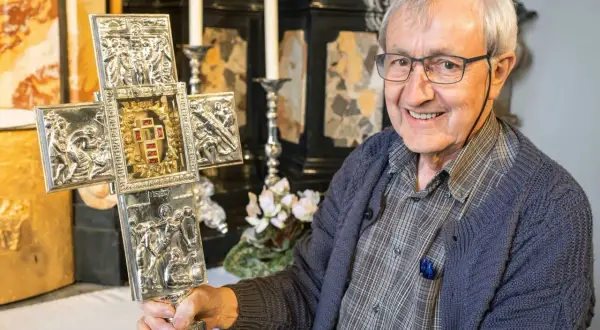 Ein Mann hält einen verzierten Kreuz mit Jesus Splitter. Die Gravuren zeigen Szenen aus dem Leben Jesu.
