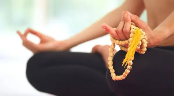 Person in Meditation, Hände halten Mala-Kette, um den perfekten Mantra finden zu können.