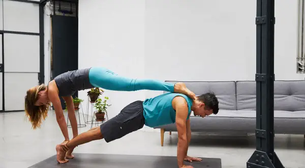 Paar übt anspruchsvolle Acroyoga Figuren. Sie bilden eine stabile Basis für kreative Posen.