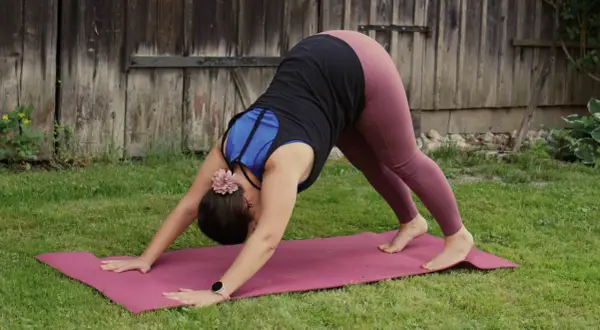 Frau in der Yoga-Pose herabschauender Hund, die sanft ihren Körper dehnt, vielleicht zur Vorbereitung auf die Schwangerschaft.