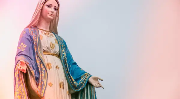 Statue der Maria, die ihre Hand ausstreckt, als würde sie zu einer Marienandacht im Mai einladen.