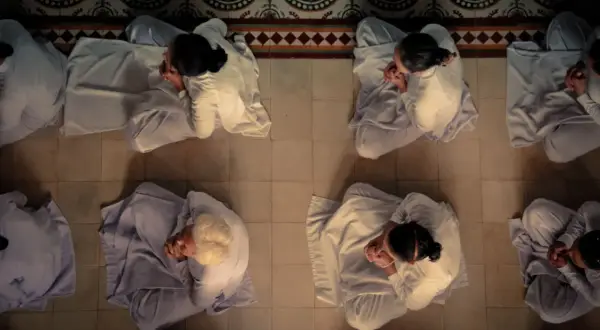 Frauen in weißen Gewändern praktizieren Herz Meditation, ihre Hände gefaltet, in stiller Andacht auf dem Boden sitzend.