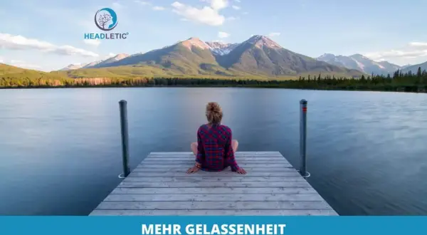 Eine Frau sitzt auf einem Steg am See, blickt auf Berge. Ähnlich gelassen wie Kardinal Ratzinger in stiller Kontemplation.
