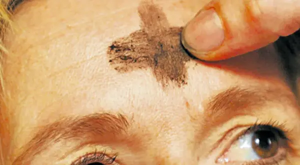 Ein Finger zeichnet ein Aschekreuz auf die Stirn. Dies ist ein Symbol für Aschermittwoch und den Beginn der Fastenzeit.