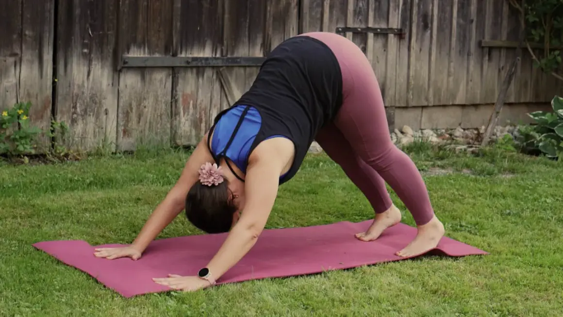 Frau in der Yoga-Pose herabschauender Hund, die sanft ihren Körper dehnt, vielleicht zur Vorbereitung auf die Schwangerschaft.