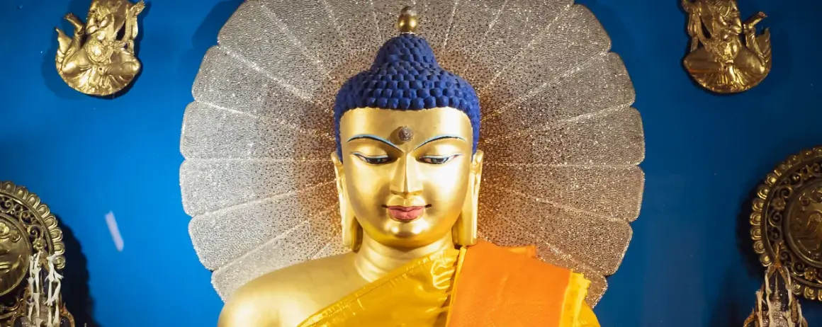 Goldene Buddha-Statue mit blauem Haar und orangefarbenem Gewand vor einem schimmernden Heiligenschein. Ein Wegweiser, wie werde ich buddhist.
