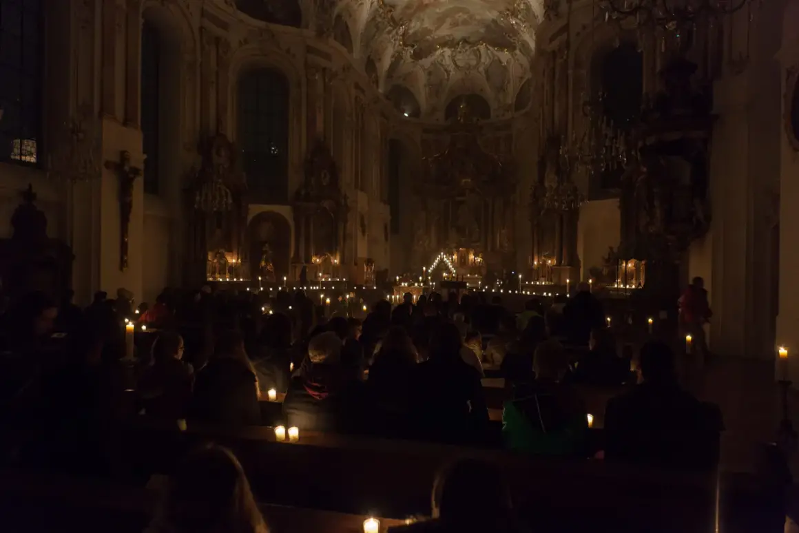 Menschen sitzen in einer dunklen Kirche, beleuchtet von Kerzen. Eine feierliche Vigil in der Kirche.