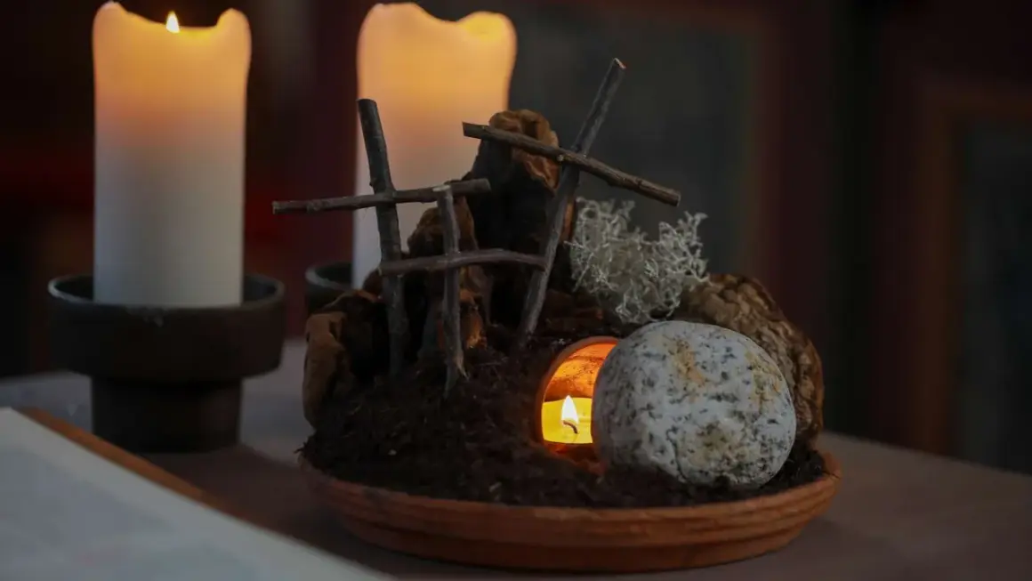 Grab und Kerzenlicht symbolisieren die **heilige Woche**. Ein Stein liegt vor dem Eingang einer Höhle, aus der ein Licht scheint.
