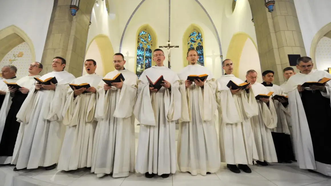 Mönche in weißen Roben singen gregorianik musik aus Büchern in einer Kirche.