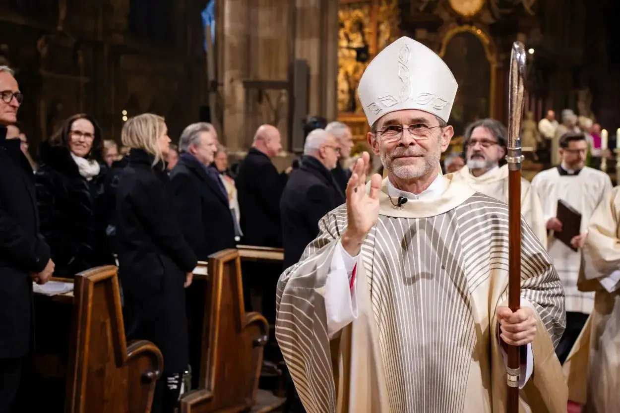 Bischof winkt der Gemeinde in der Kirche zu. Er tr&auml;gt Mitra und Stab, ein Zeichen seiner W&uuml;rde, die er ad multos annos aus&uuml;bt.