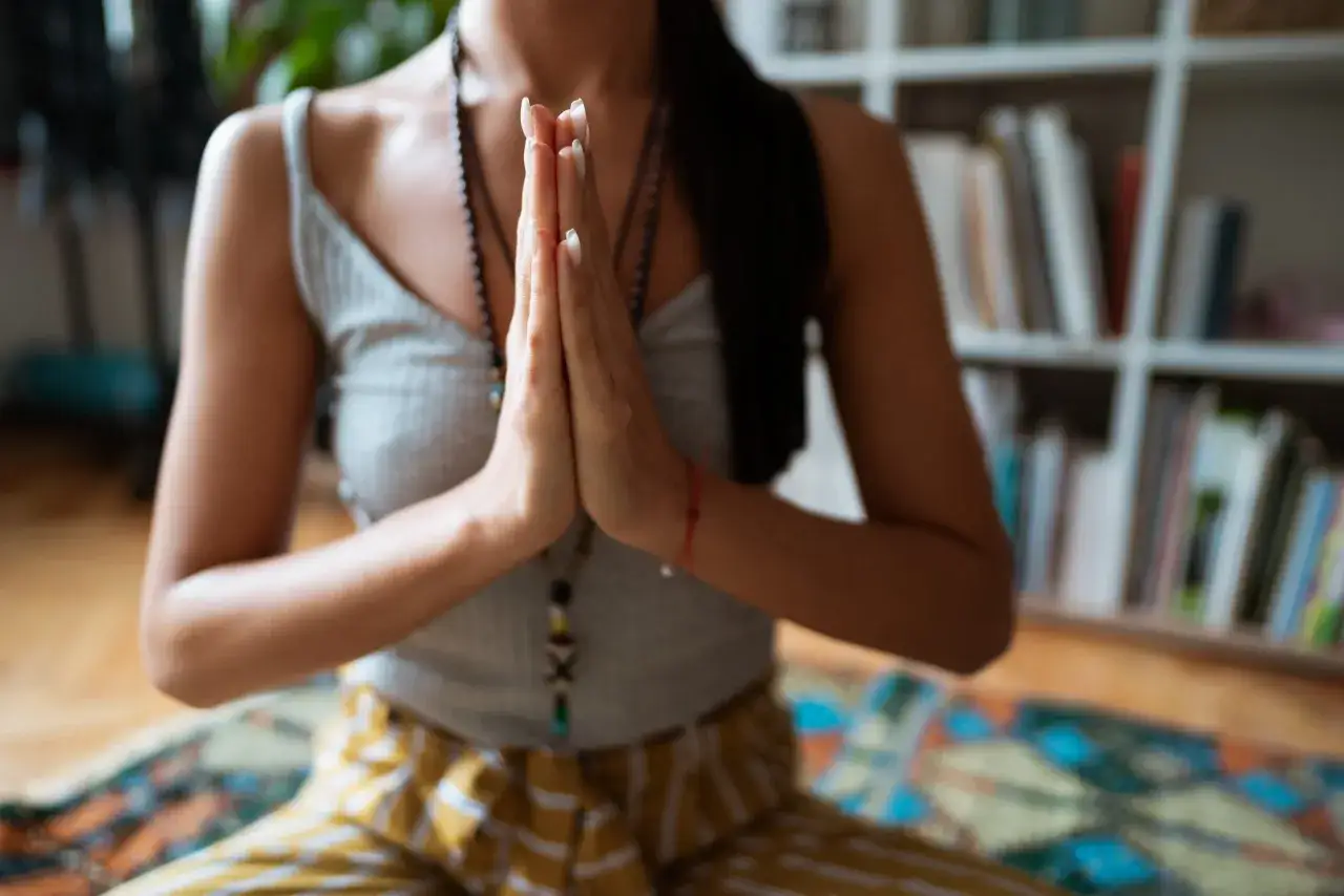 Frau in Yoga-Kleidung mit gefalteten Händen, die die Namaste-Bedeutung von 