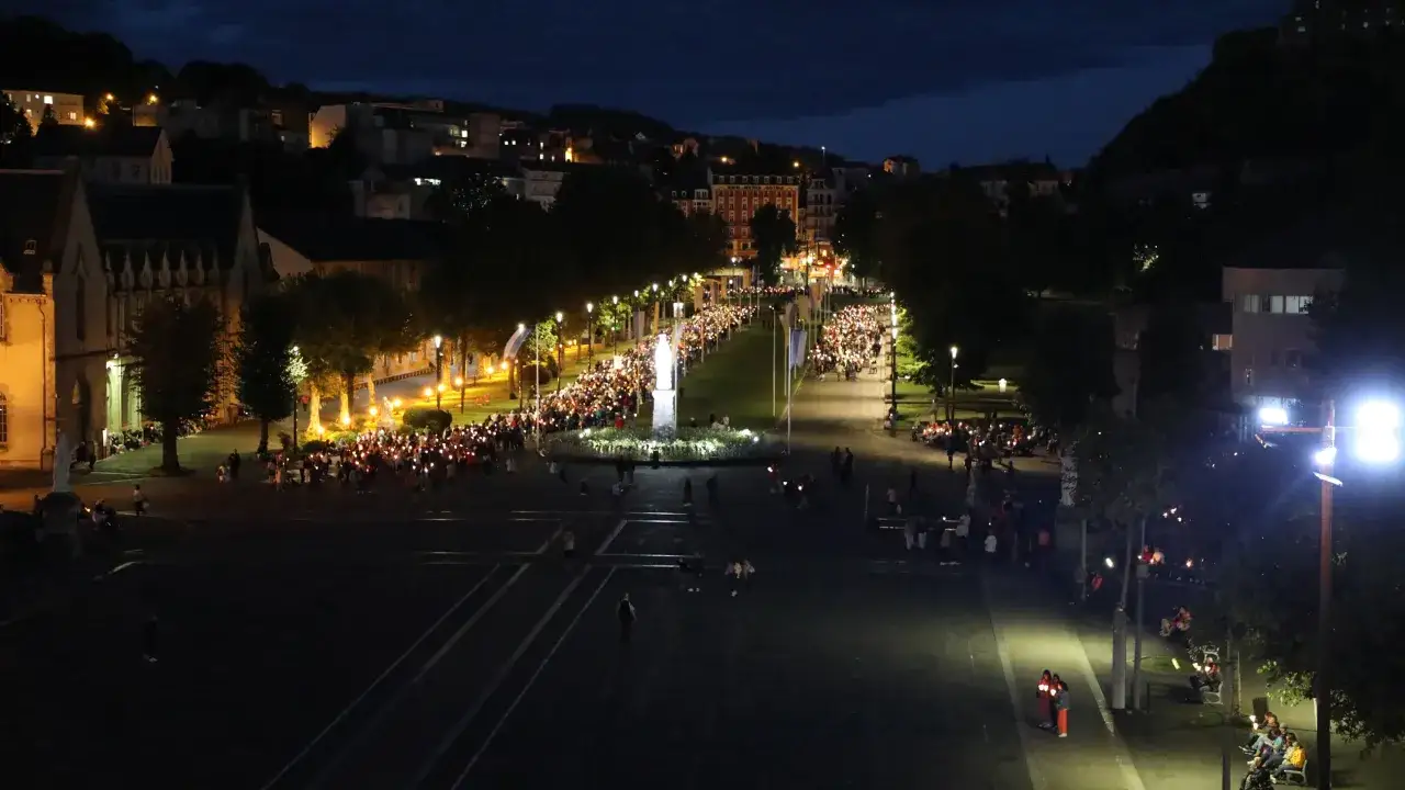 Eine feierliche Lichterprozession in Lourdes zieht sich durch die Nacht. Tausende von Kerzen erhellen den Weg der Pilger.