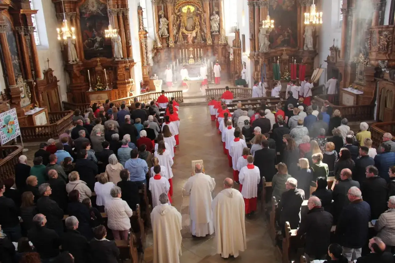 Menschen in einer Kirche, die einem feierlichen Gottesdienst folgen. Was ist ein Hochamt? Hier wird es gezeigt, mit Priestern und Gl&auml;ubigen.