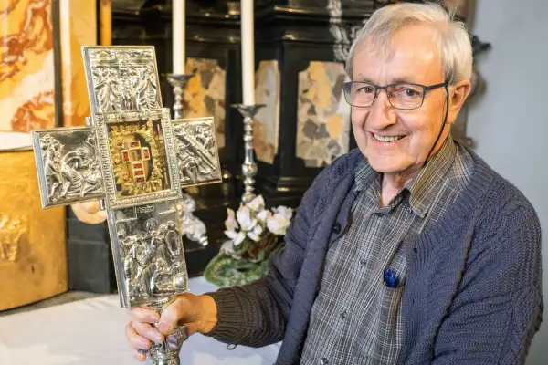 Ein Mann hält einen verzierten Kreuz mit Jesus Splitter. Die Gravuren zeigen Szenen aus dem Leben Jesu.