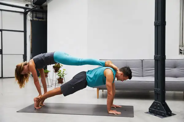 Paar übt anspruchsvolle Acroyoga Figuren. Sie bilden eine stabile Basis für kreative Posen.