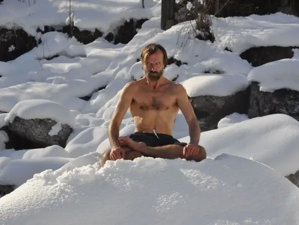 Mann in Lotussitz im Schnee, praktiziert die Wim Hof Methode.