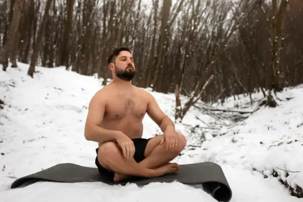 Mann in der Kälte, übt Wim Hof Atmung im Schnee.