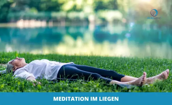 Frau genießt eine friedliche Meditation im Liegen auf einer grünen Wiese am See.