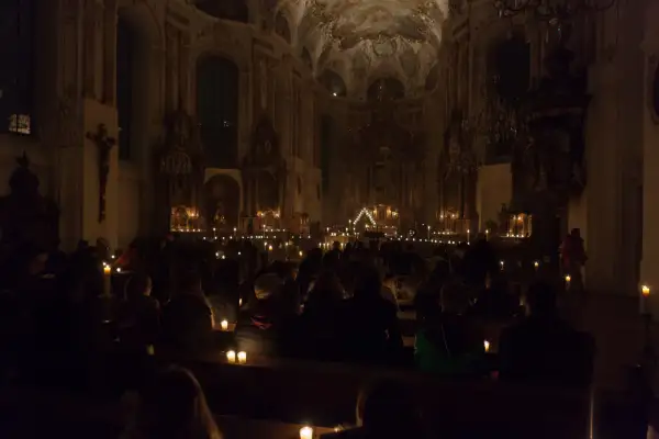 Menschen sitzen in einer dunklen Kirche, beleuchtet von Kerzen. Eine feierliche Vigil in der Kirche.