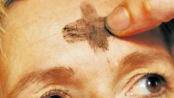 Ein Finger zeichnet ein Aschekreuz auf die Stirn. Dies ist ein Symbol für Aschermittwoch und den Beginn der Fastenzeit.